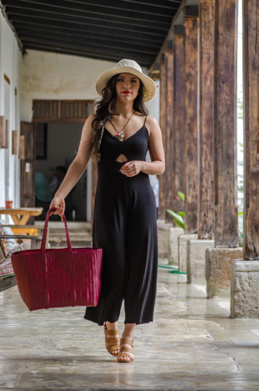 Woman carrying a burgundy handwoven recycled-plastic Beach Bag tote along a colonial corridor in Antigua Guatemala